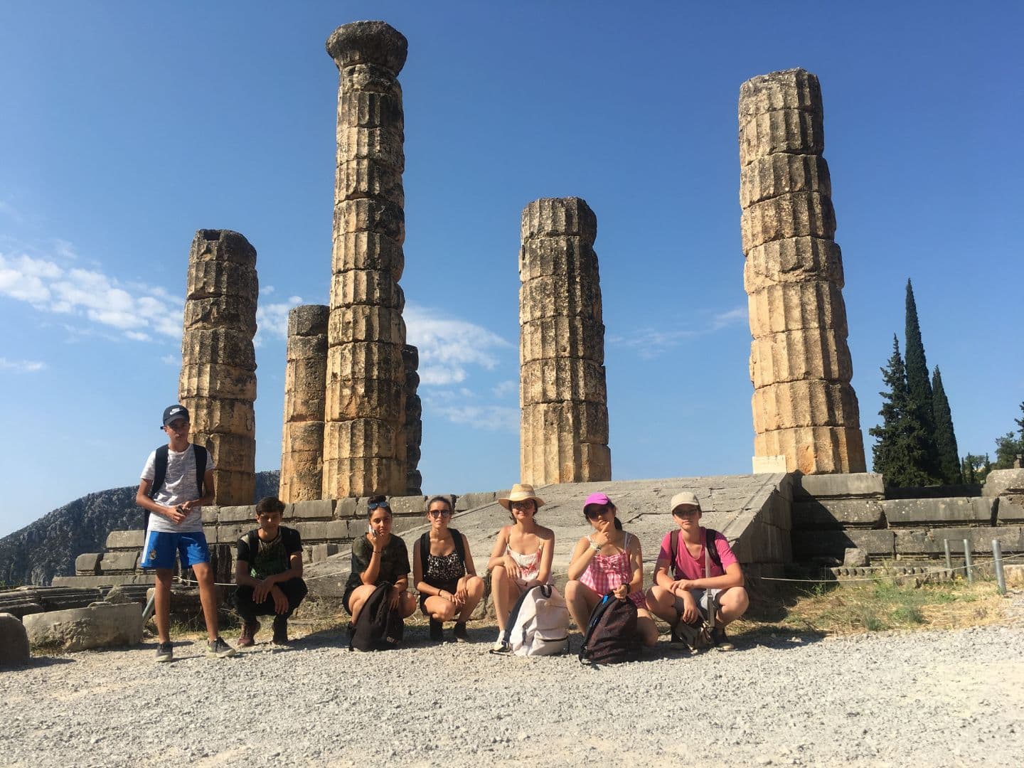 Des adolescents en voyage en Grèce prennent une photo devant des colonnes .