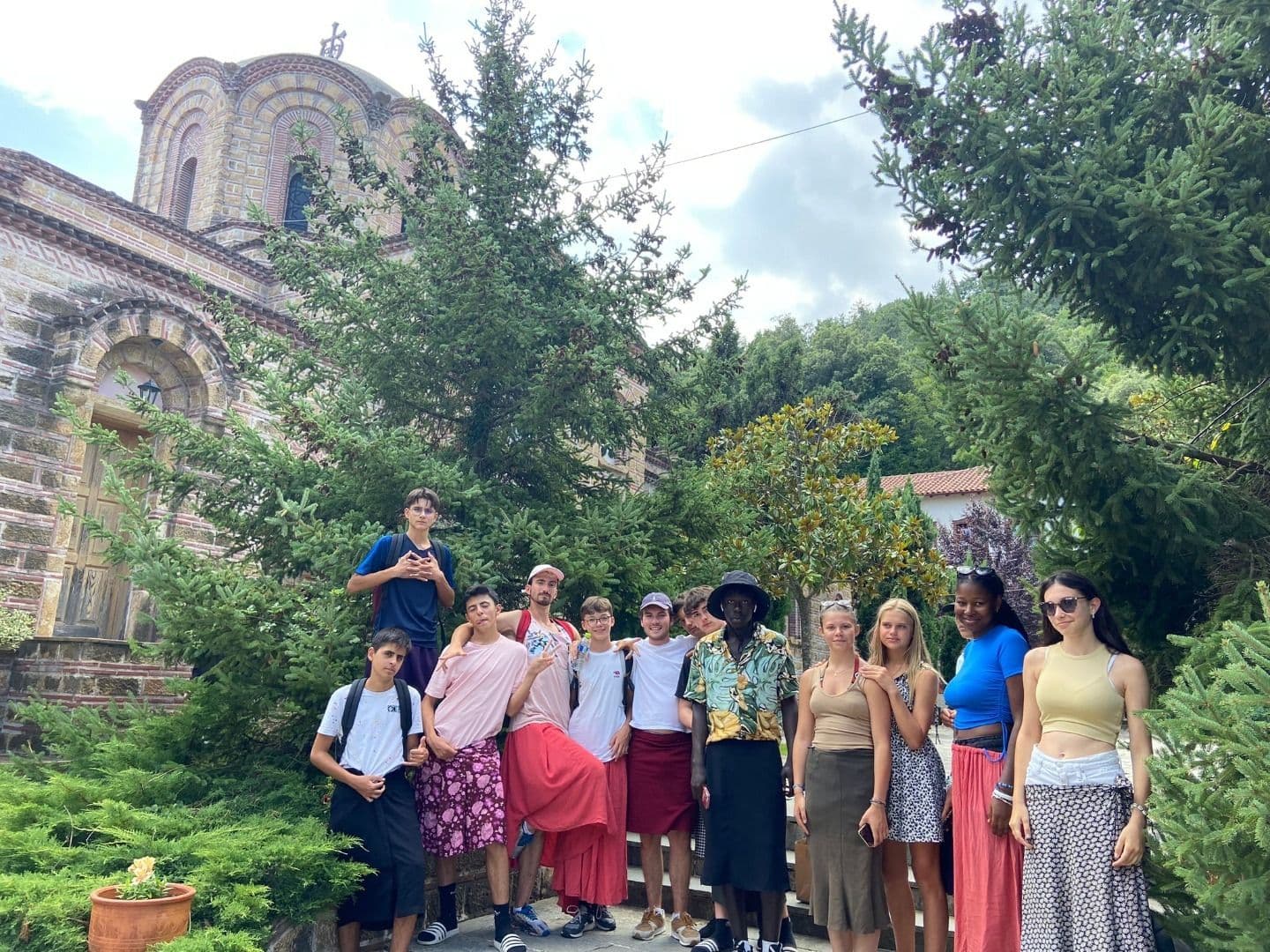 Des adolescents en vacances en Grèce prennent une photo devant un monument.