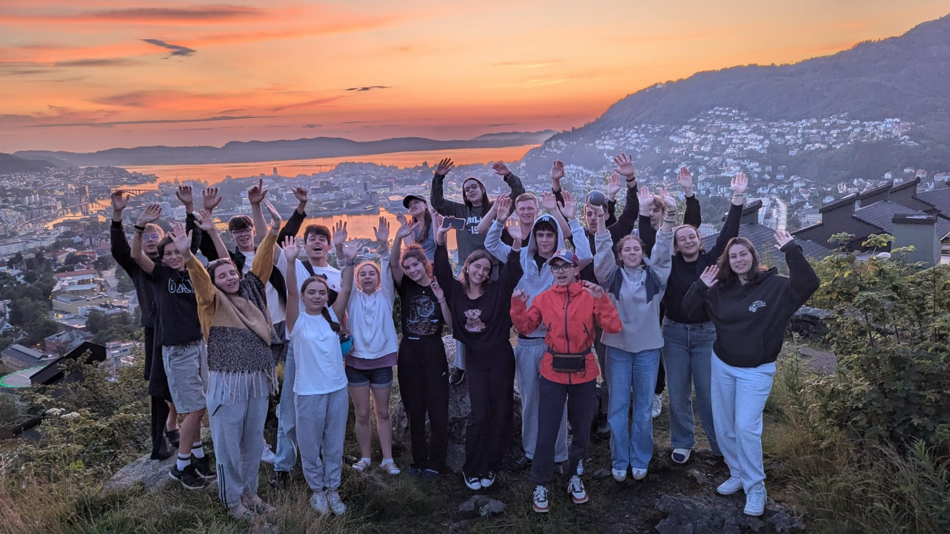Groupe d’adolescents en colonie CEI admirant un coucher de soleil sur Bergen et les fjords de Norvège.