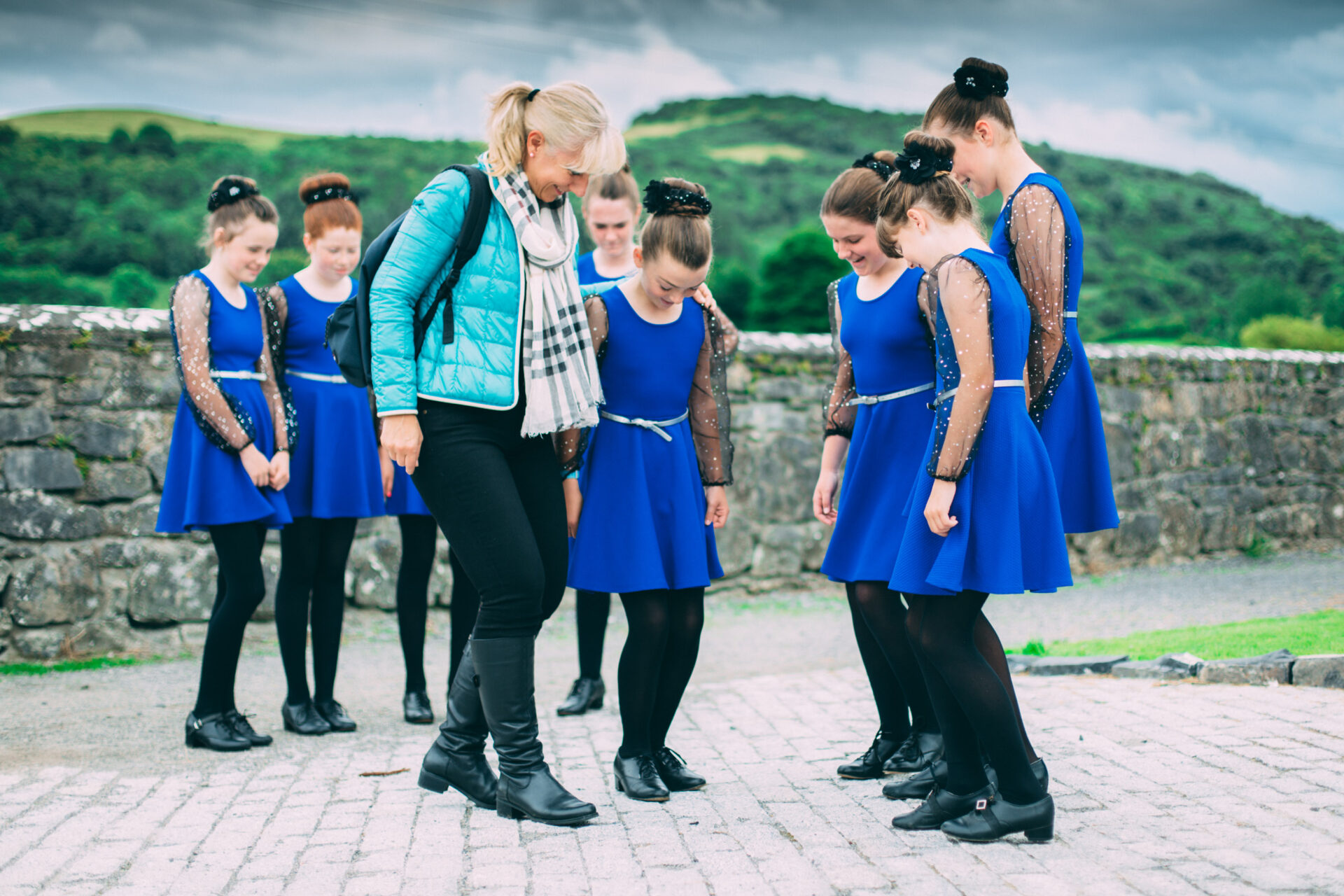 Des enfants participent à un cours de danse irlandaise avec leur professeur, suivant ses mouvements avec enthousiasme dans une salle lumineuse.
