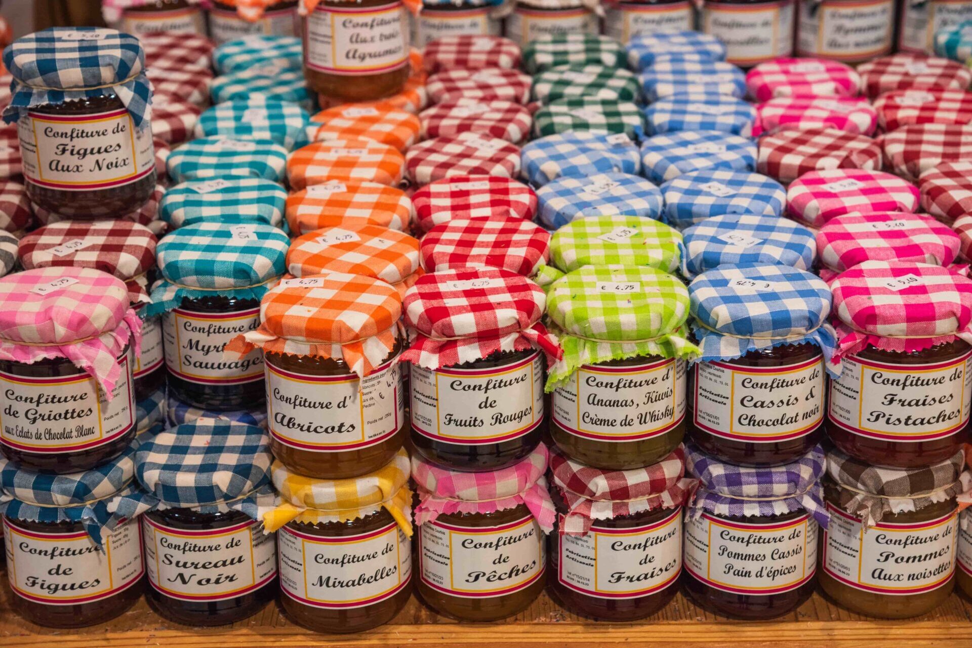 Colorful jars of artisan jam in a French market, popular souvenirs from France to bring home.
