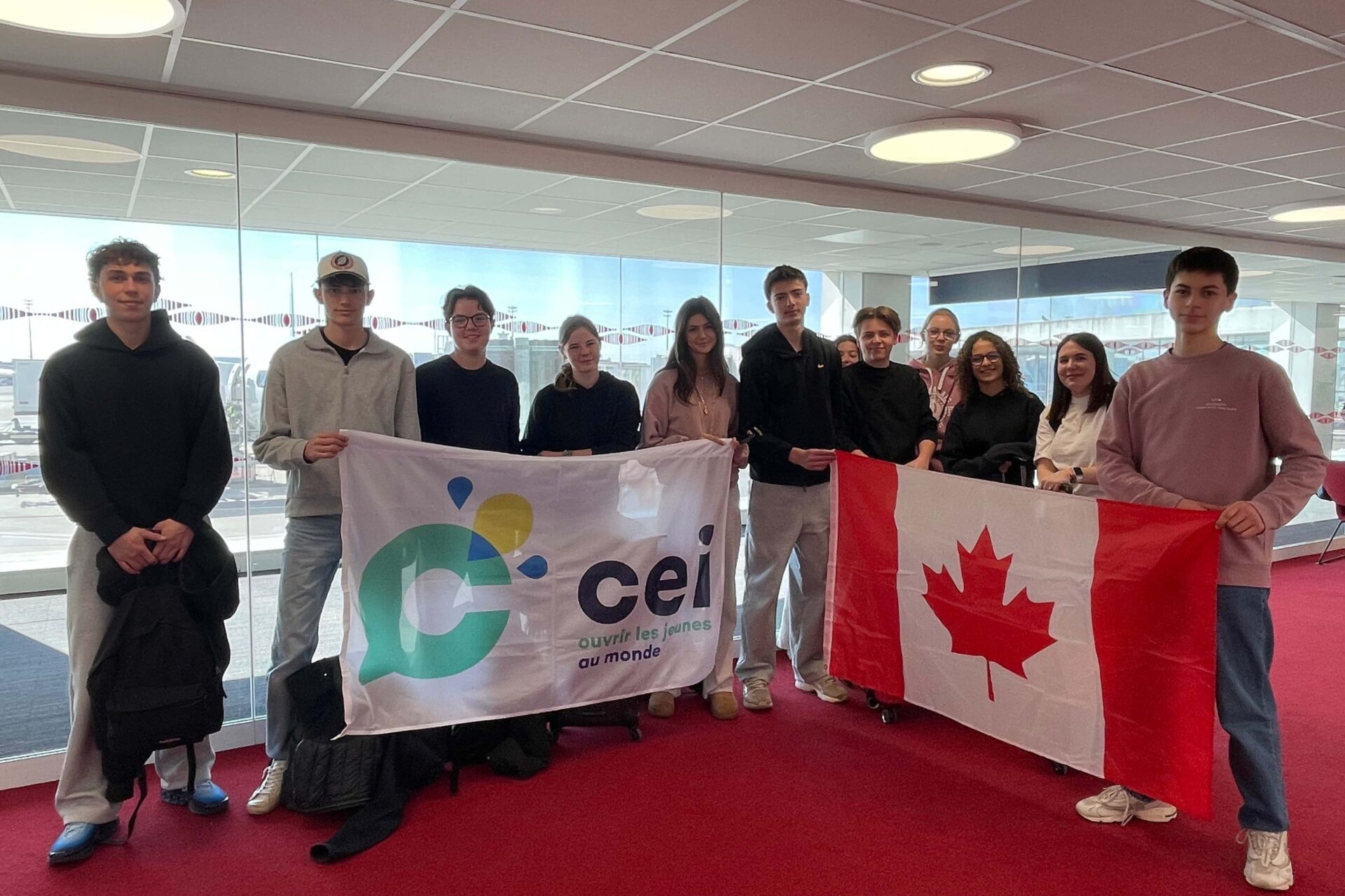 Jeunes participants CEI tenant les drapeaux du CEI et du Canada avant leur départ en programme scolaire.

