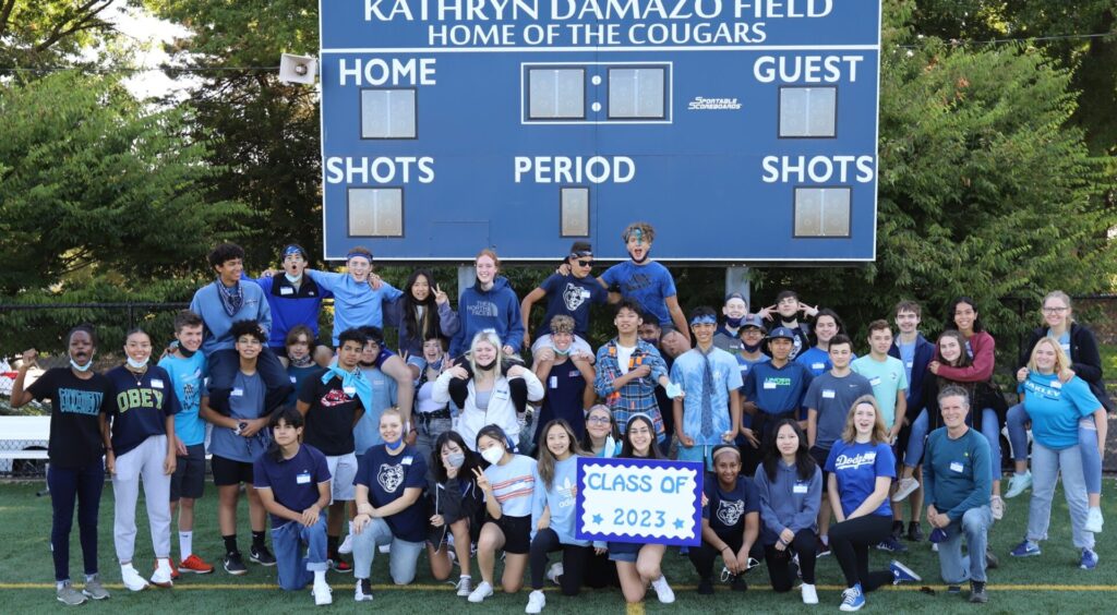 Groupe d’élèves internationaux CEI posant devant un tableau de score dans un lycée aux États-Unis.