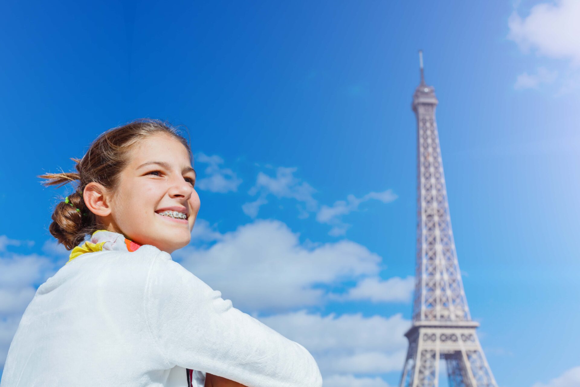 Smiling student with Eiffel Tower in background – symbol of discovery, learning, and international friendship through CEI camps in France.