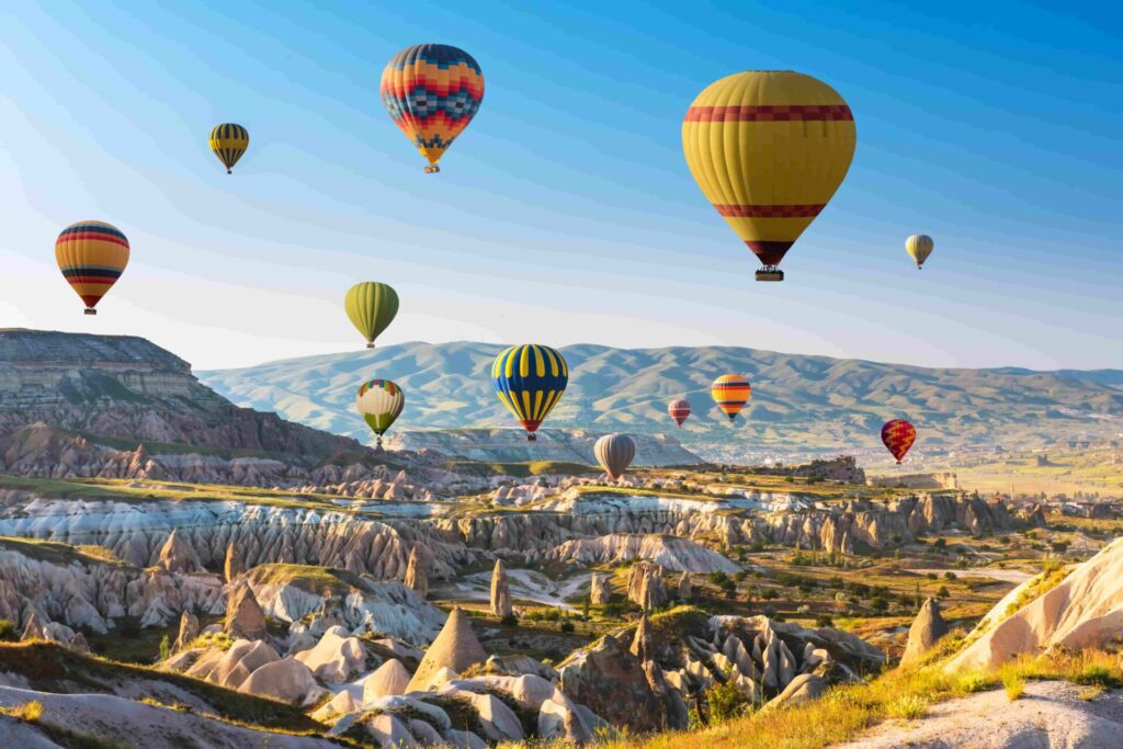 Montgolfières colorées survolant les formations rocheuses de Cappadoce au lever du soleil pendant une colonie de vacances.
