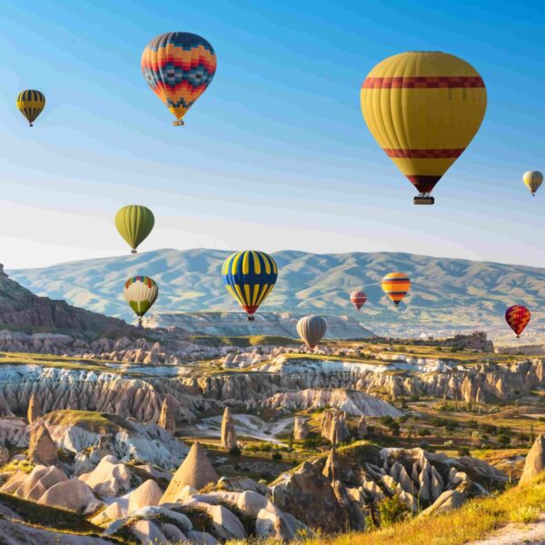 Montgolfières colorées survolant les formations rocheuses de Cappadoce au lever du soleil pendant une colonie de vacances.