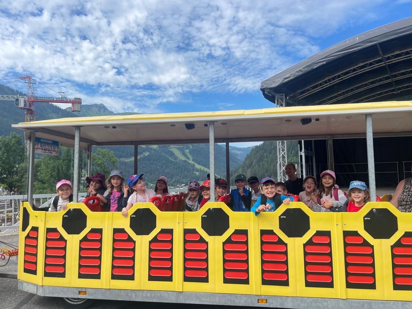 Enfants souriants dans un petit train jaune lors d’une colonie de vacances été à Châtel.