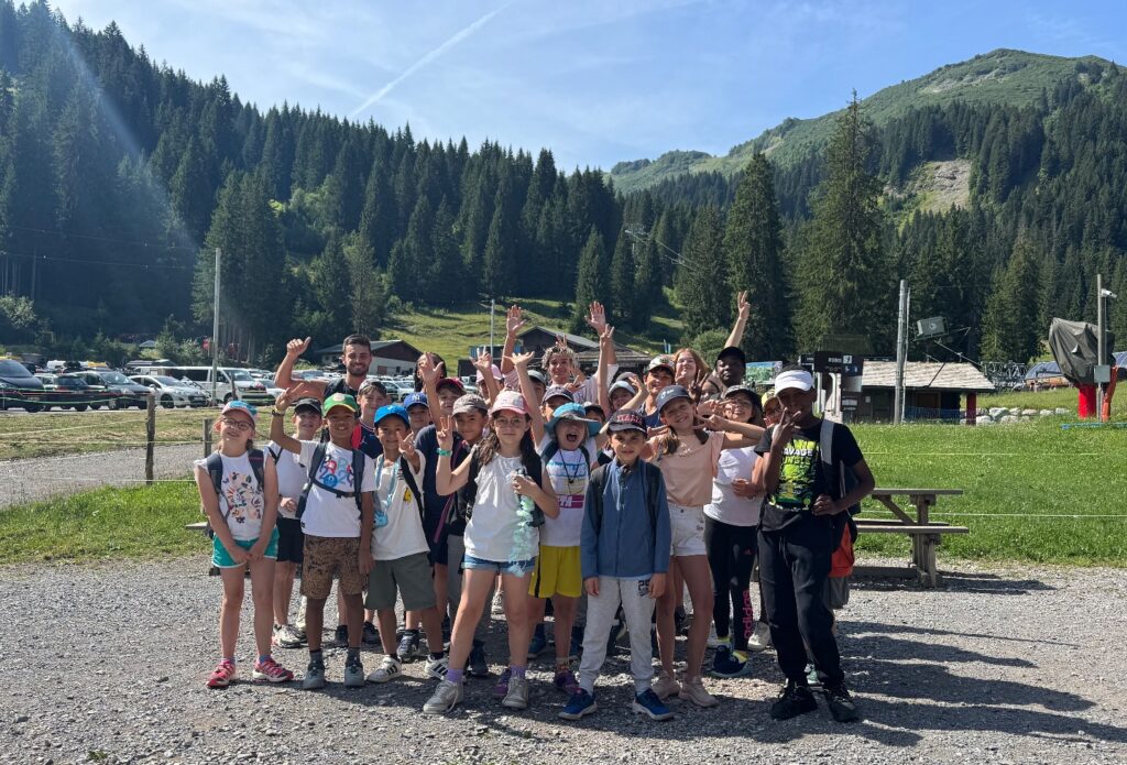 Groupe d’enfants et d’animateurs posant en montagne pendant une colonie de vacances été.