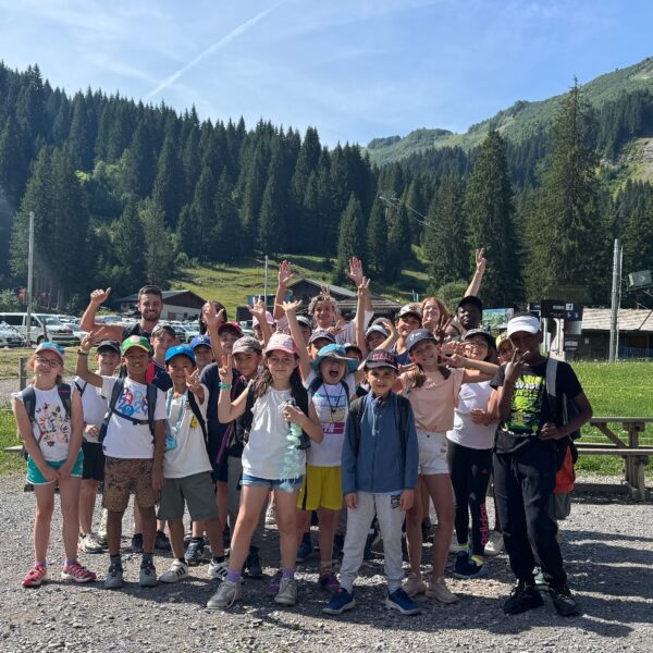 Groupe d’enfants et d’animateurs posant en montagne pendant une colonie de vacances été.