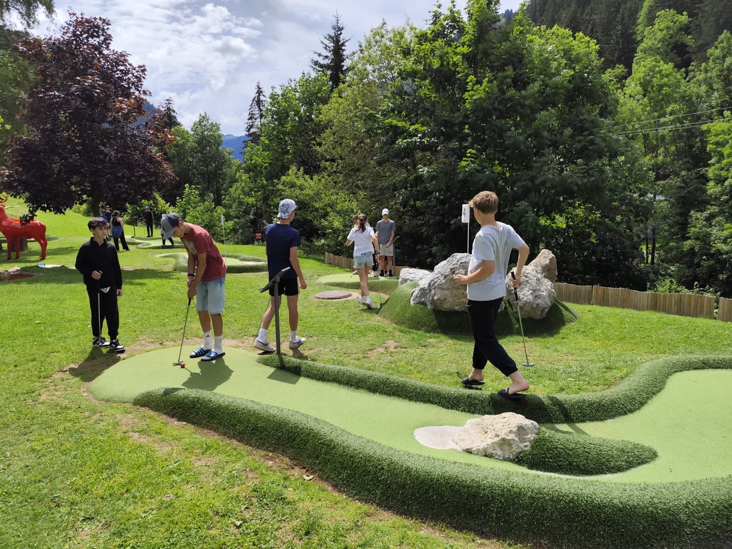 Enfants jouant au mini-golf sur un terrain en montagne pendant une colonie de vacances été.